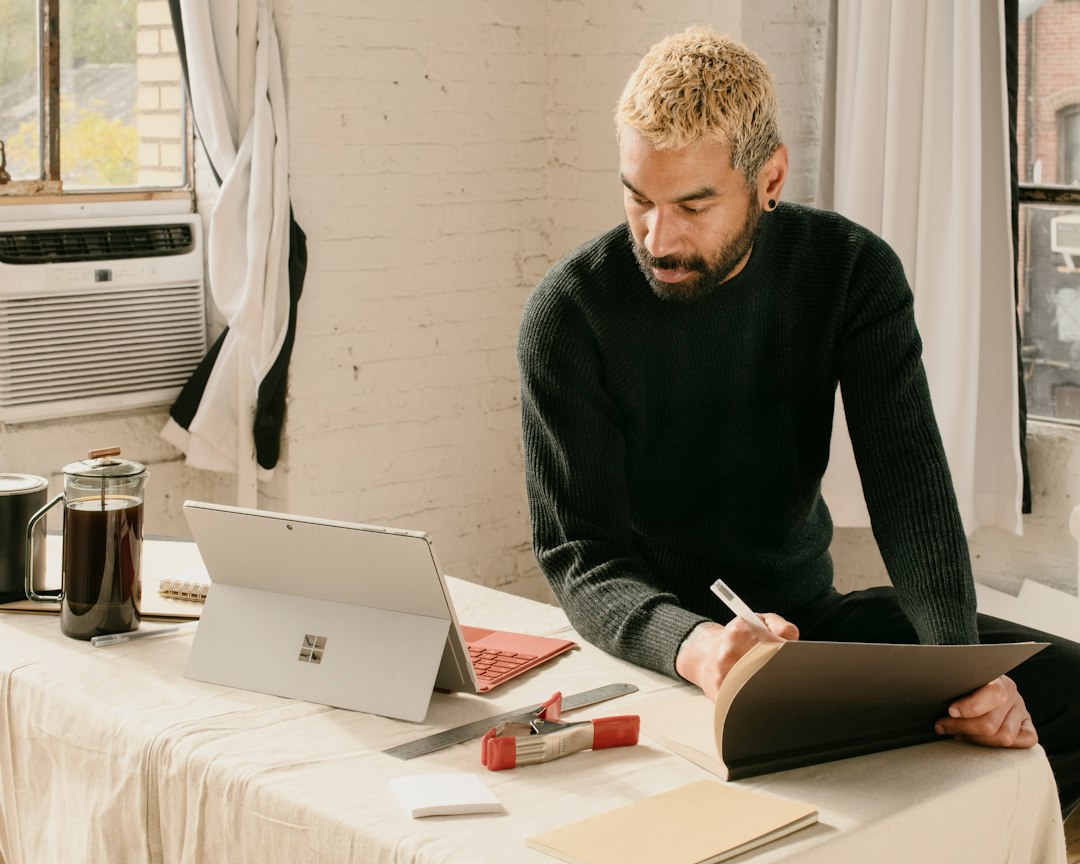A concerned homeowner sits at their kitchen table, carefully reviewing a home repair contract with a pen in hand, focusing on the details.