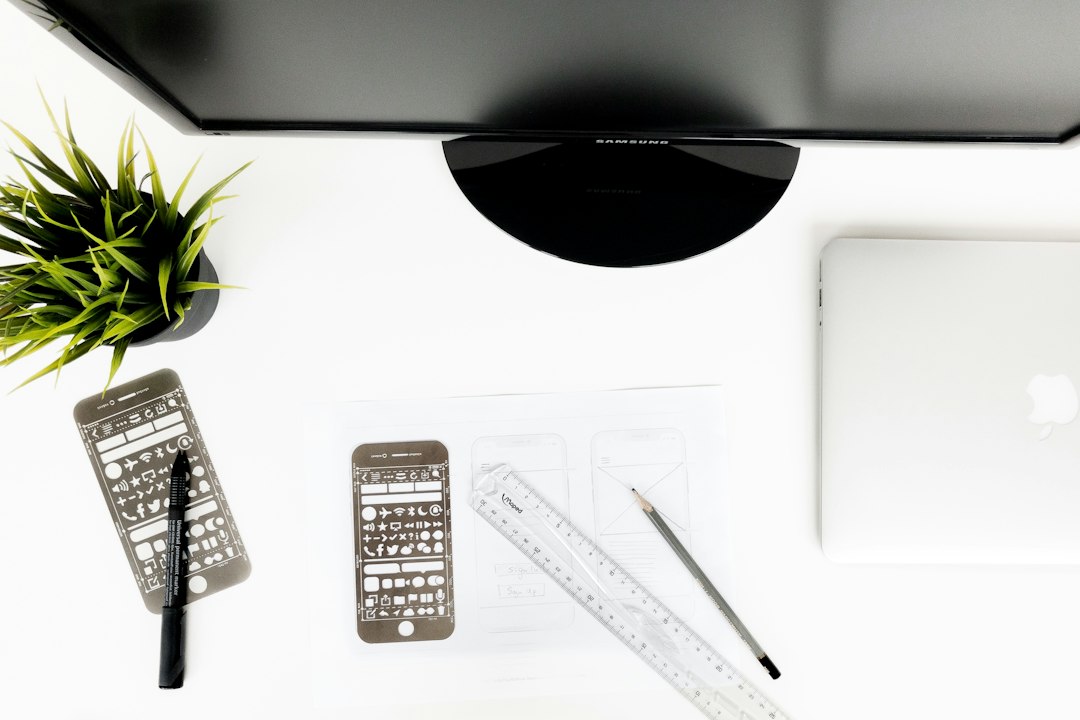 A person at a minimal desk uses a calculator while reviewing house plans, illustrating the importance of calculating an agent's total value over just the commission rate.